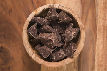 top view dark chocolate chunks in wood bowl on table