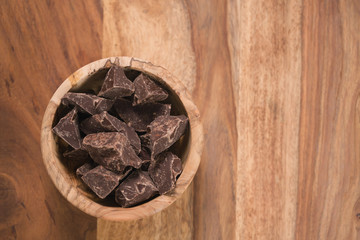 top view dark chocolate chunks in wood bowl on table
