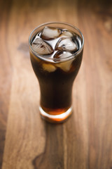 cola with ice in glass on wood table