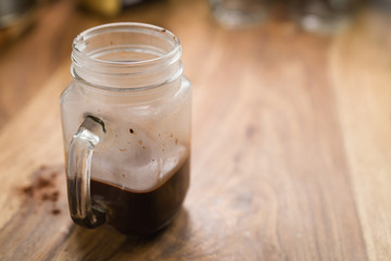 making warm cocoa in glass mug jar on wood table