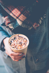 The girl holding the paper cup of coffee with milk and caramel in her tender hand. Sunny spring afternoon.