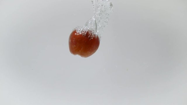 Red apple falling into water, Ultra Slow Motion