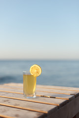 Glass of cold drink with lemon on table sunbed or table on beach