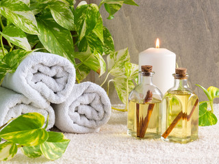 Obraz na płótnie Canvas Spa treatment and massage products with towels, oil bottles, candles and plants on stone background