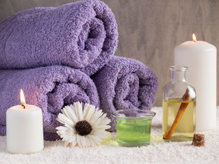 Spa treatment and massage products with towels, oil, flowers and candles on stone background