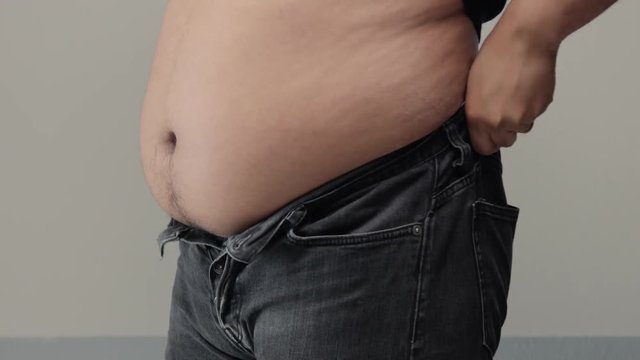 overweight man closeup of belly trying to put up jeans Trying fasten a button