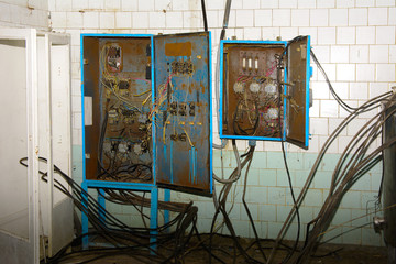Old dismantled and rusty electrical panel assembly on an abandoned and destroyed factory against a backdrop of chaos. Destruction and vandalism. Ukraine.