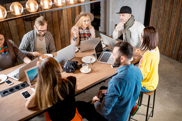 Young coworkers dressed casually sitting with laptops during the conference in the modern loft workspace
