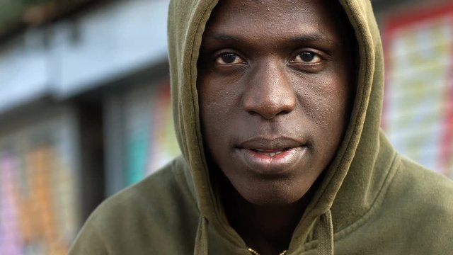 Hooded handsome black african man turning and looking camera- Urban background
