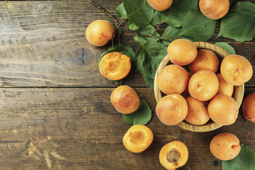Naklejka na ściany i meble Delicious ripe apricots in a wooden bowl on the table close-up
