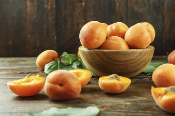 Delicious ripe apricots in a wooden bowl on the table close-up