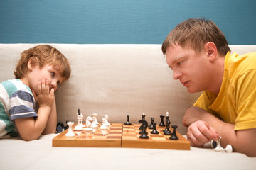 Father and son are playing chess while spending time together at home