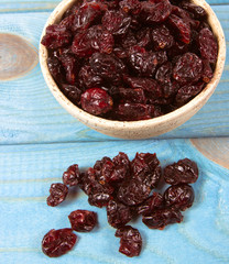Dry cranberries fruit in the bowl, on the wood background.