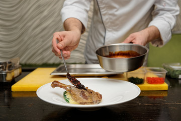 Chef is adding berry sauce to poultry dish
