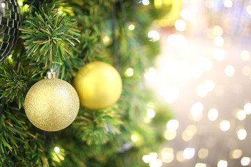 gold color Christmas ball hang on green pine tree with blurred night light new year party background for add text.