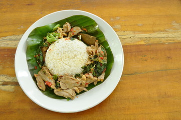 spicy fried duck meat with basil leaf and rice on fresh banana leaf