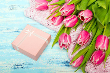 Pink tulip bouquet and gift box on blue wooden background, copy space. Beautiful flowers