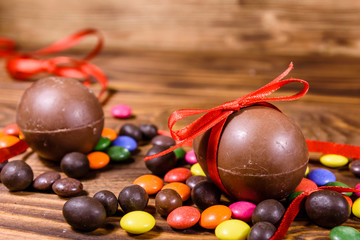 Chocolate easter eggs and multicolored candies on wooden table