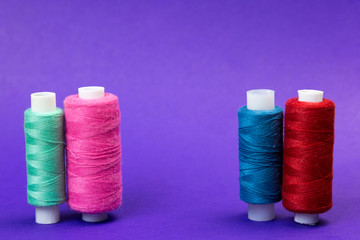 Several reels with threads on a blue background. The thread is stretched between the multi-colored thread coils.