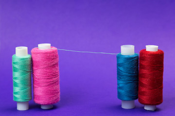 Several reels with threads on a blue background. The thread is stretched between the multi-colored thread coils.