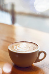 Top view of hot coffee cappuccino latte art in white ceramic cup on wooden plate with small plant on marble table. Coffee cup top view on old wooden. Coffee cup in coffee shop