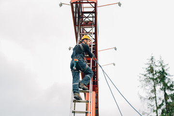 Industrial climber climbing stairs to the billboard