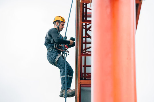 Industrial climber hangs a poster on a billboard