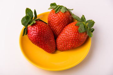 Three strawberries on a yellow plate