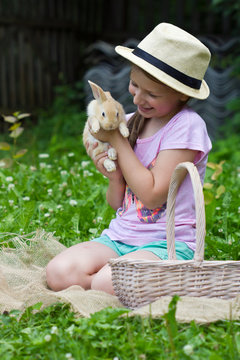 beautiful girl holds in the hands of a small rabbit, teen girl and rabbit on the green grass.