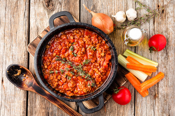 classic italian bolognese sauce stewed in cauldron with ingredients on wooden table, top view - 194833117