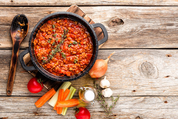 classic italian bolognese sauce stewed in cauldron with ingredients on wooden table, top view,...