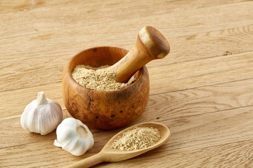 Wooden mortar and pestle with garlic and grind spices on rustic table, close-up, selective focus