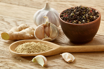 Composition of powder spices on spoon and different sorts of spicies on wooden table background, selective focus