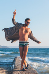 Happy young man dancing on the dock at the beach