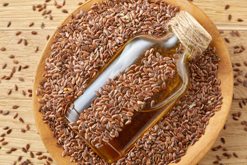 Top view closeup picture flax seeds and linseed oil in a glass bottle on a wooden background, shallow depth of field.