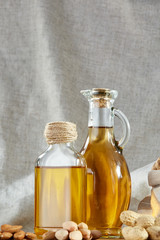 Aromatic oil in a glass jar and bottle with pistachio in bowl on wooden table, close-up