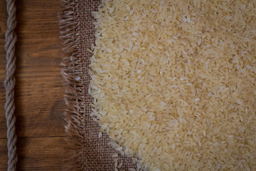 Rice. Steamed rice on wood background and burlap top view
