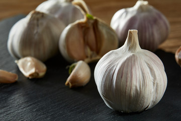 Garlic close up on wooden plate on rustic background, shallow depth of field, selective focus, macro