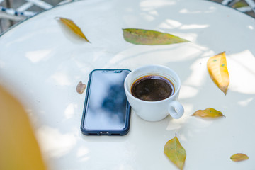 Close up smart phone and white coffee cup on the white table with white white background