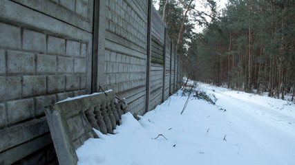 old wall next to snowy road in forrest