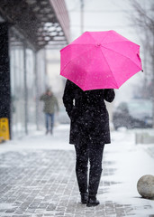 Woman with pink umbrella on snowy day.