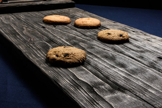 Chip-cookies on a dark old wooden trayon a blue background.