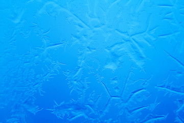 Frosty patterns on window glass on blue background