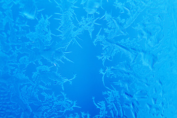 Frosty patterns on window glass on blue background