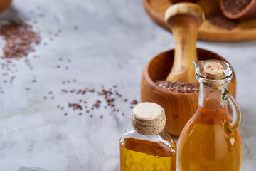 Flax seeds in bowl and flaxseed oil in glass bottle on light textured background, top view, close-up, selective focus