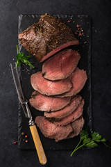 sliced  roast beef on slate board, black background