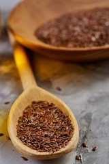Flax seeds in bowl and flaxseed oil in glass bottle on light textured background, top view, close-up, selective focus