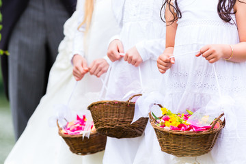 Fototapeta na wymiar Wedding couple bride and groom with flower children or bridesmaid in white dress and flower baskets