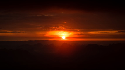 Beautiful nature Landscape of sky at Sunrise in the morning, Floating over the vast mountains. The colors of the sky are red and orange. The sun shines through the forest and the mist. 