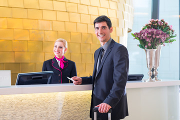 Man in Hotel check in at reception or front office being given key card